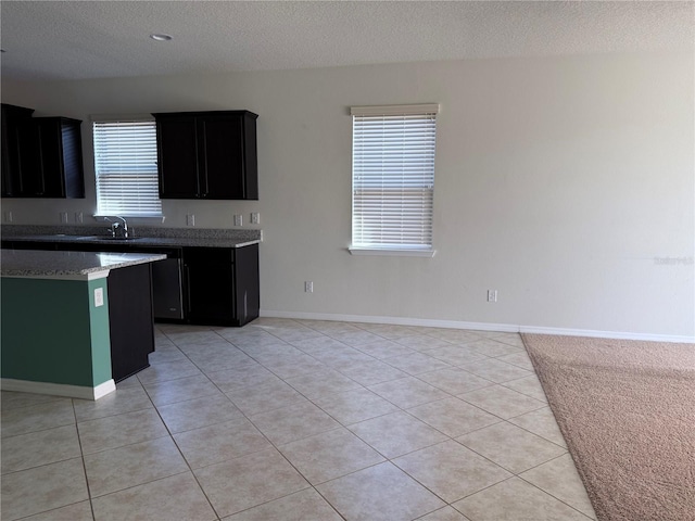 kitchen with sink, a textured ceiling, a healthy amount of sunlight, and light tile patterned flooring