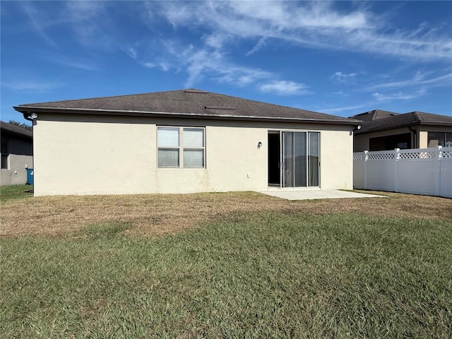 back of property with a yard and a patio