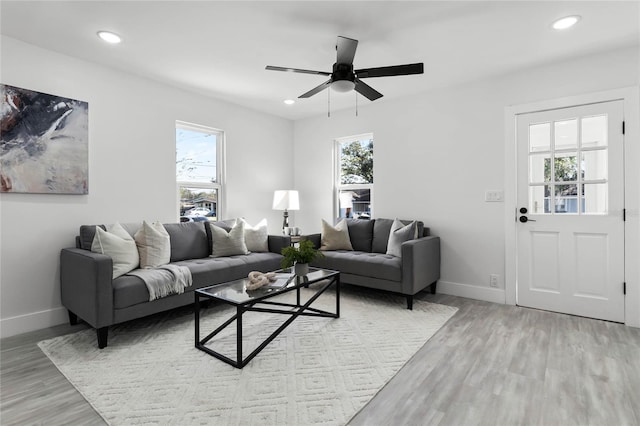 living room with light hardwood / wood-style floors, ceiling fan, and a healthy amount of sunlight