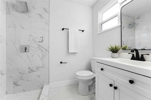 bathroom featuring a tile shower, vanity, and toilet