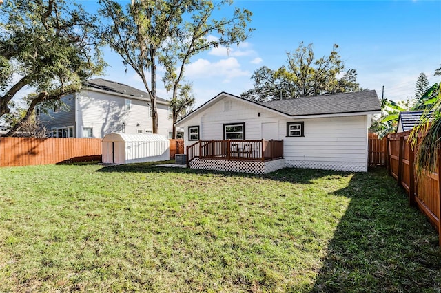 back of property with a storage shed, a deck, and a yard