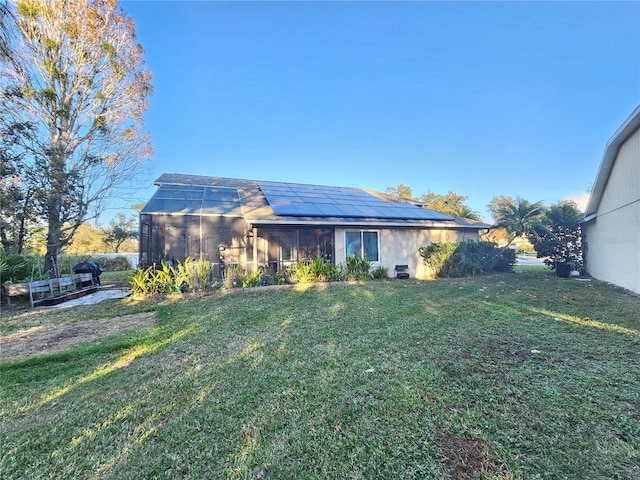 rear view of house featuring solar panels, a yard, and a lanai