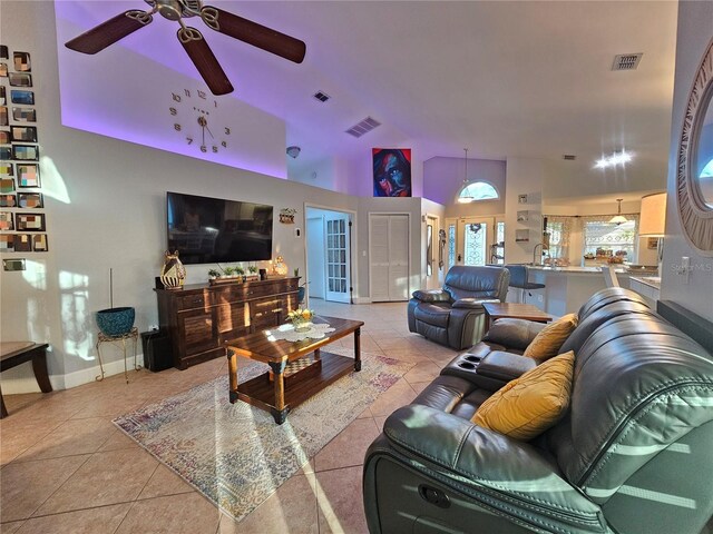 tiled living room with ceiling fan and high vaulted ceiling