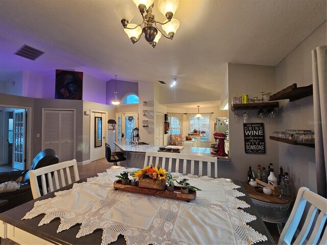 dining space with a textured ceiling, lofted ceiling, tile patterned floors, and a notable chandelier