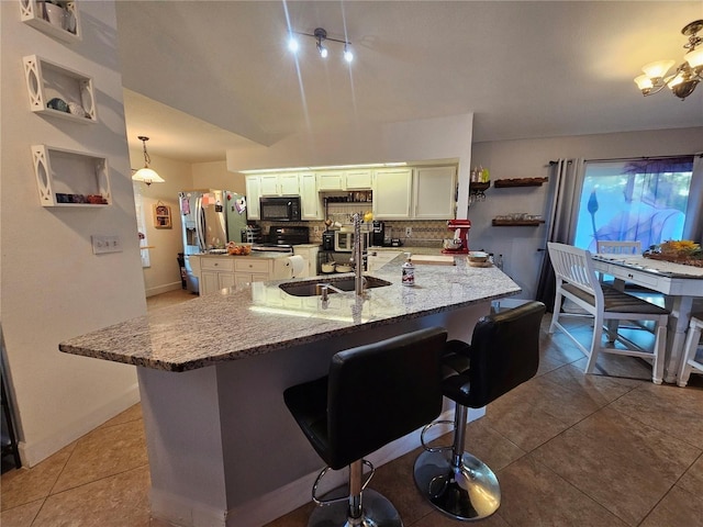 kitchen featuring stainless steel fridge, light stone countertops, tasteful backsplash, decorative light fixtures, and a kitchen bar