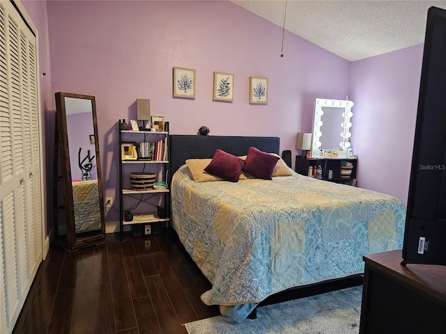 bedroom featuring a textured ceiling, lofted ceiling, a closet, and dark hardwood / wood-style floors