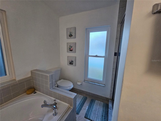 bathroom featuring tile patterned floors, a relaxing tiled tub, and toilet