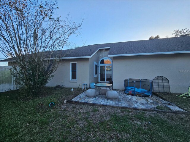 back of house with a lawn and a patio