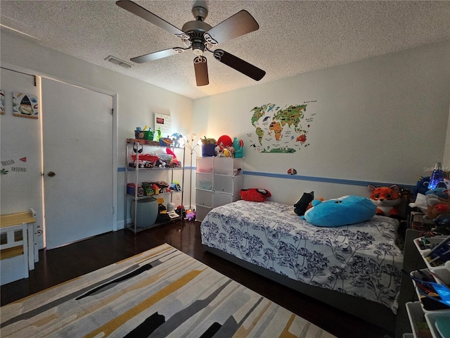 bedroom featuring a textured ceiling, ceiling fan, and dark wood-type flooring