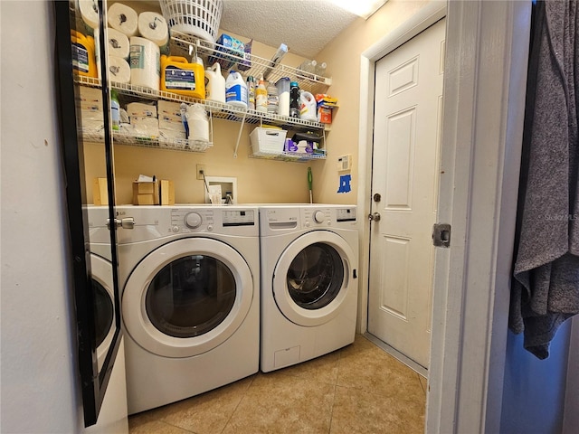 laundry room featuring a textured ceiling, washing machine and dryer, and light tile patterned floors