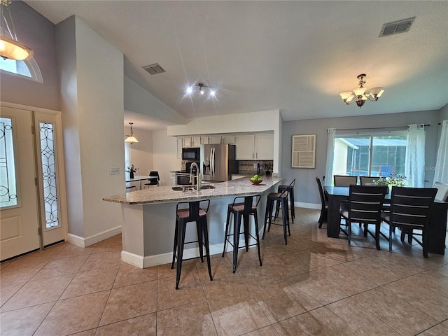 1022 Bartlett Ct, Oviedo, FL 32765 - kitchen featuring stainless steel fridge with ice dispenser, black microwave, a peninsula, a kitchen breakfast bar, and light stone counters