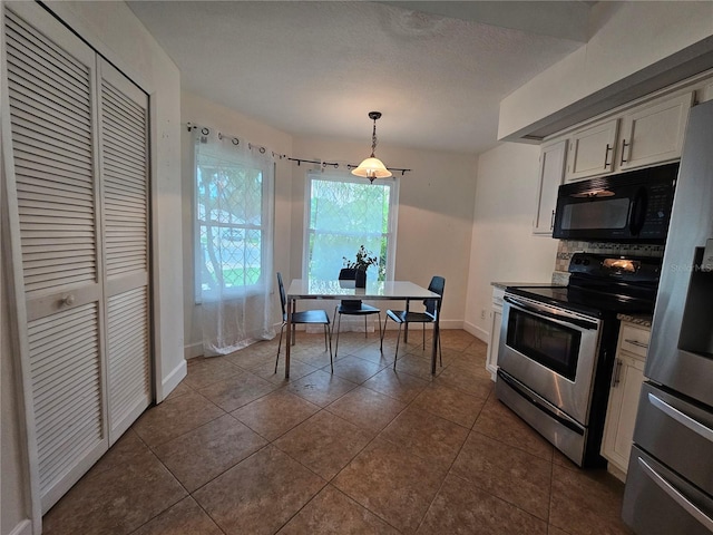 1022 Bartlett Ct, Oviedo, FL 32765 - kitchen featuring appliances with stainless steel finishes, dark tile patterned flooring, white cabinetry, tasteful backsplash, and pendant lighting