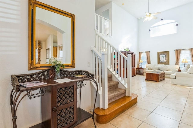 stairway with ceiling fan, tile patterned flooring, and a high ceiling