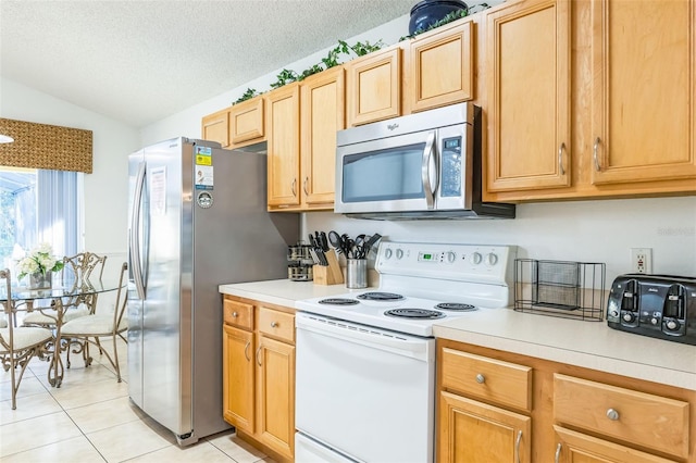 kitchen featuring a textured ceiling, light tile patterned flooring, lofted ceiling, and appliances with stainless steel finishes