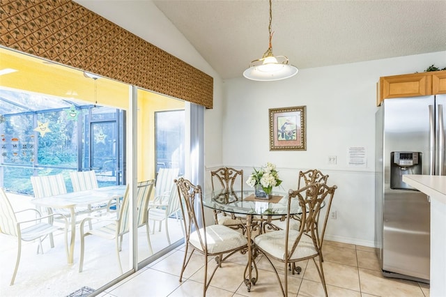 dining area with a textured ceiling, lofted ceiling, and light tile patterned flooring