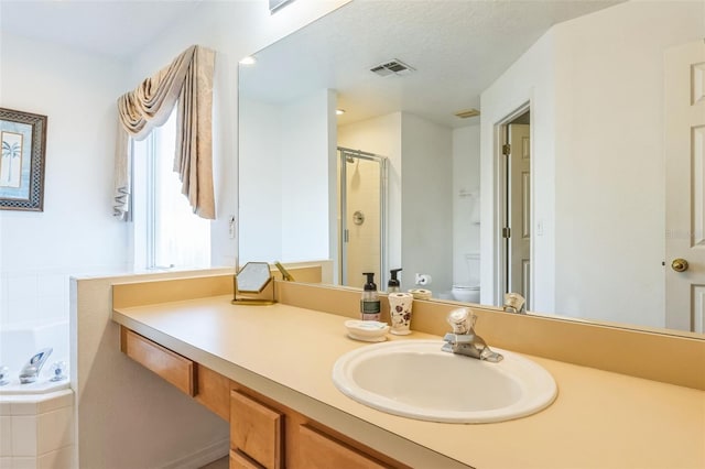 full bathroom featuring vanity, independent shower and bath, and toilet