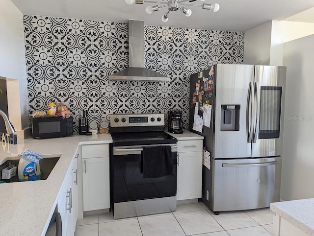 kitchen featuring wall chimney range hood, sink, appliances with stainless steel finishes, light stone counters, and white cabinetry