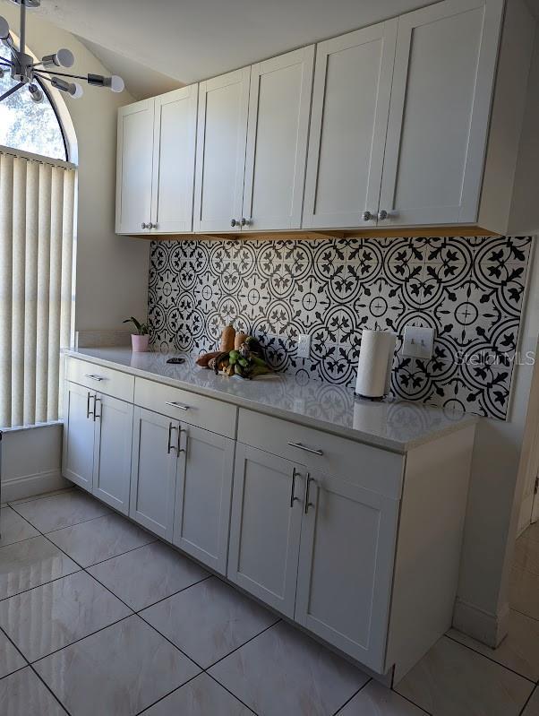 kitchen featuring white cabinets, tasteful backsplash, vaulted ceiling, and ceiling fan