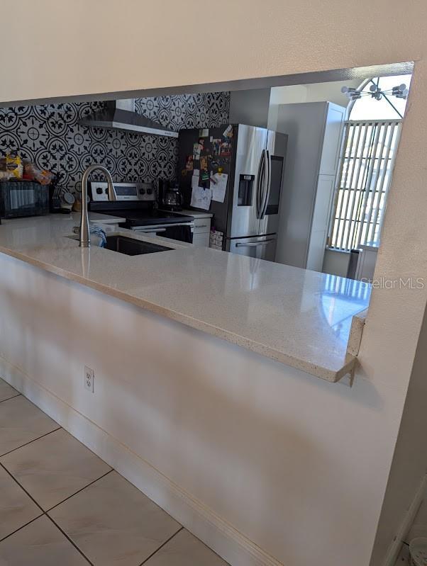 kitchen with wall chimney range hood, stainless steel appliances, and sink