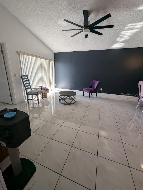 unfurnished room with lofted ceiling, a textured ceiling, and light tile patterned floors