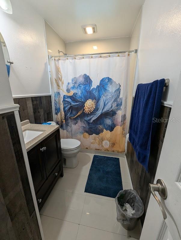 bathroom featuring tile patterned floors, vanity, curtained shower, and toilet