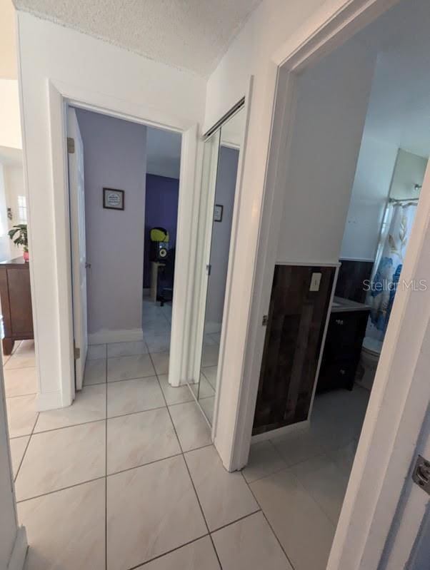 hallway with a textured ceiling and light tile patterned flooring