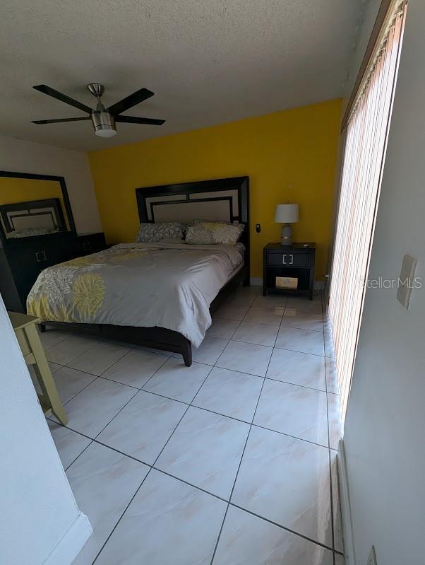 tiled bedroom featuring ceiling fan and a textured ceiling