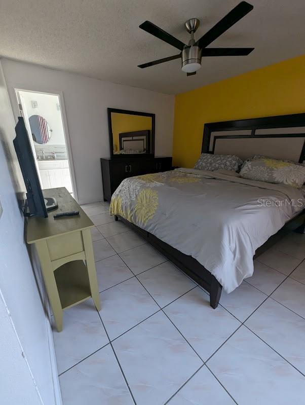 tiled bedroom with a textured ceiling and ceiling fan