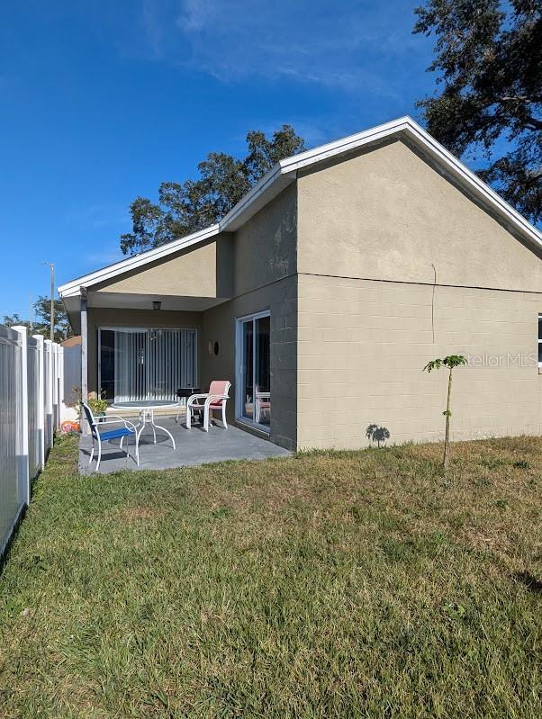 rear view of property with a lawn and a patio area