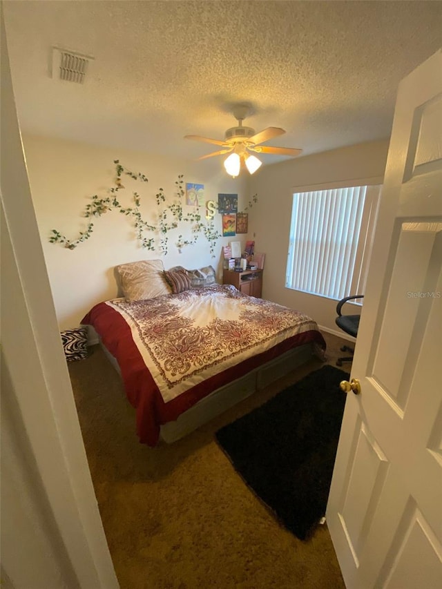 bedroom with ceiling fan, carpet floors, and a textured ceiling