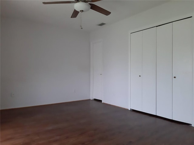 unfurnished bedroom with ceiling fan, dark wood-type flooring, and a closet