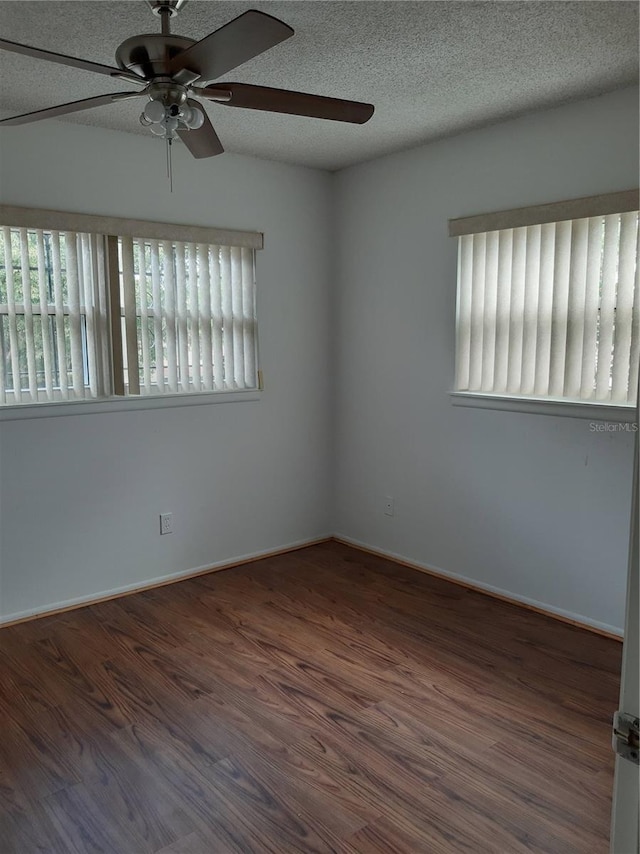 spare room featuring a textured ceiling, ceiling fan, and dark wood-type flooring