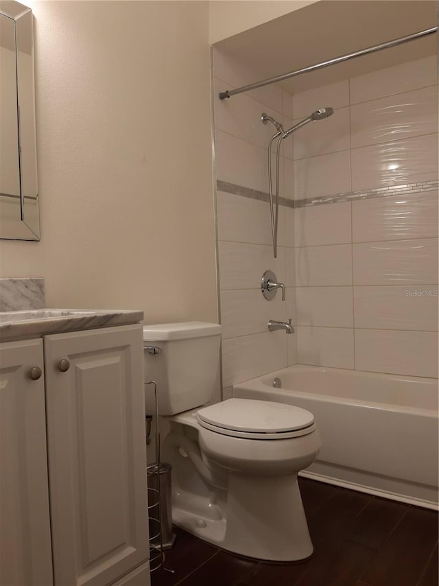 full bathroom with tiled shower / bath, vanity, and toilet