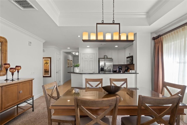 carpeted dining room featuring a tray ceiling and crown molding