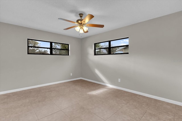 empty room featuring ceiling fan, light tile patterned flooring, and a textured ceiling