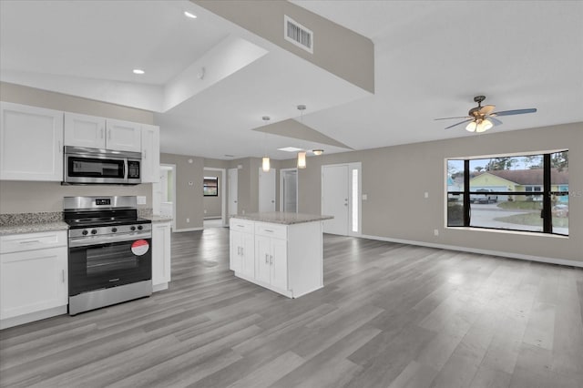 kitchen featuring white cabinets, light wood-type flooring, decorative light fixtures, and appliances with stainless steel finishes