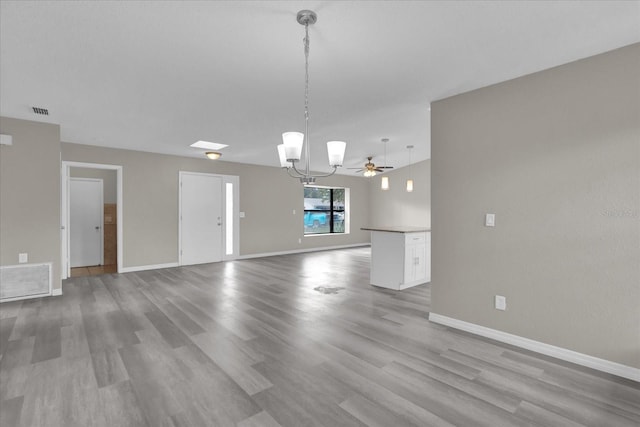 unfurnished living room featuring ceiling fan with notable chandelier and light hardwood / wood-style floors