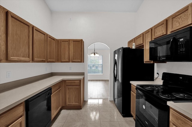 kitchen featuring an inviting chandelier, a towering ceiling, black appliances, and light tile patterned flooring