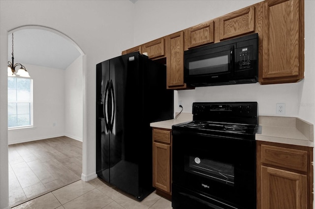 kitchen with pendant lighting, light tile patterned floors, black appliances, and an inviting chandelier