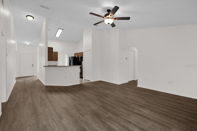 unfurnished living room featuring vaulted ceiling, dark hardwood / wood-style floors, and ceiling fan