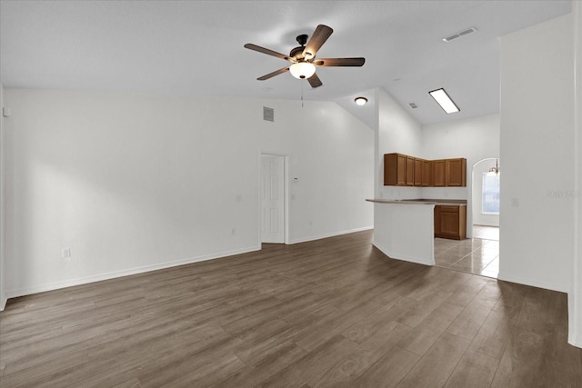 unfurnished living room with ceiling fan, high vaulted ceiling, and light wood-type flooring