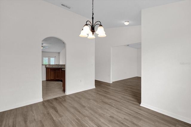 unfurnished dining area with hardwood / wood-style flooring, ceiling fan with notable chandelier, and sink