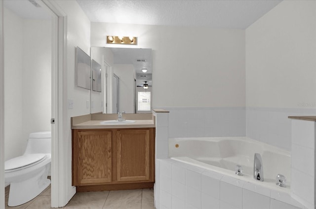 bathroom with tile patterned flooring, vanity, a relaxing tiled tub, toilet, and a textured ceiling