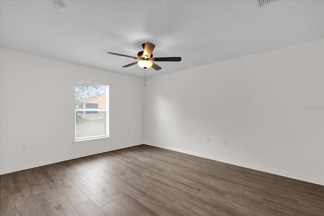 empty room with dark wood-type flooring, a textured ceiling, and ceiling fan