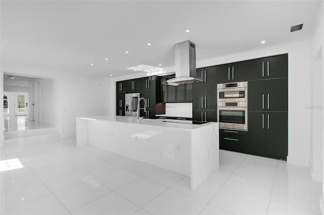 kitchen with sink, stainless steel appliances, island exhaust hood, a center island with sink, and light tile patterned floors