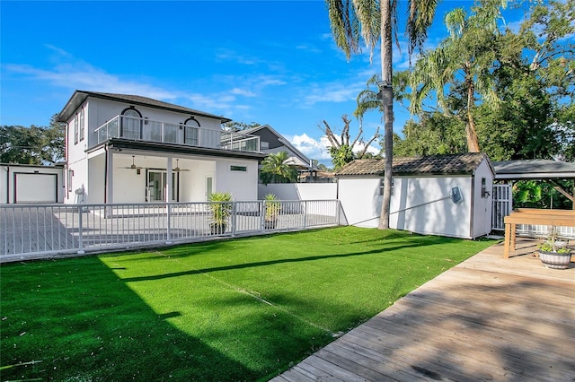 back of house with a lawn, a balcony, and a storage unit