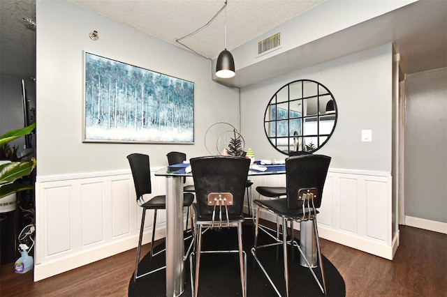 dining room featuring a textured ceiling and dark hardwood / wood-style floors