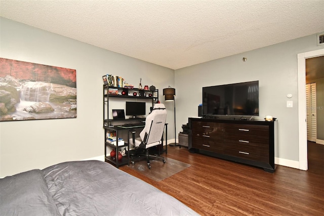 bedroom with dark hardwood / wood-style floors and a textured ceiling