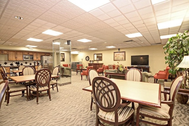 carpeted dining space with a drop ceiling