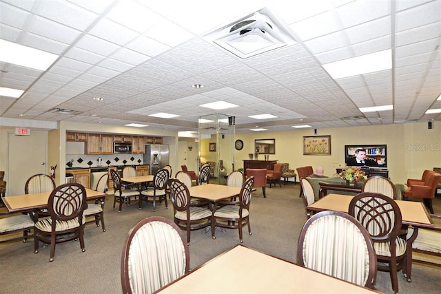 dining area with a paneled ceiling and light colored carpet